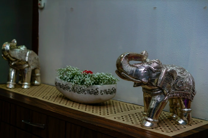 A silver elephant statue next to a bowl of flowers
