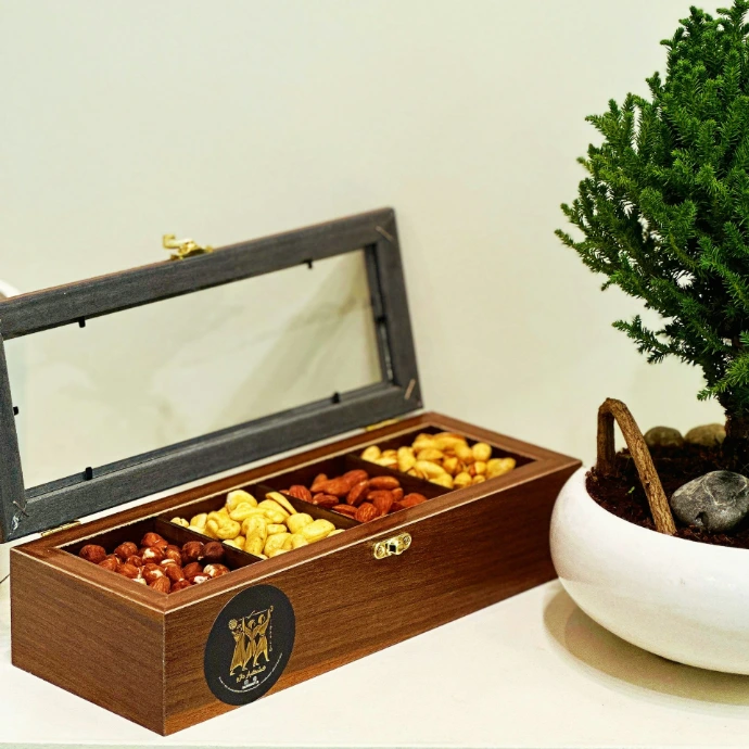 a wooden box filled with nuts next to a potted tree